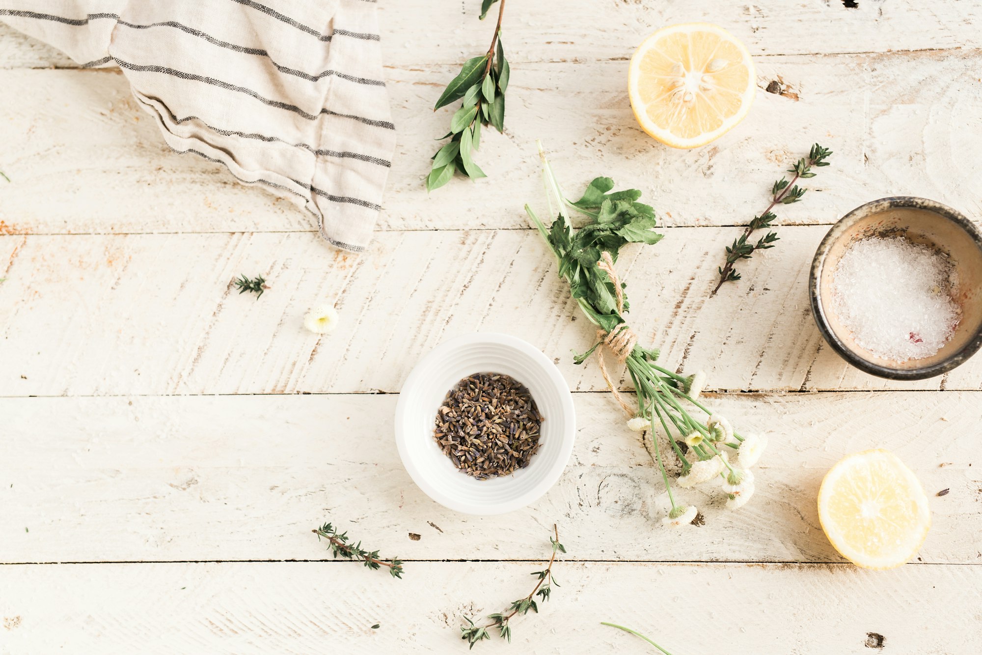 Aromatic herbs, spices and lemon on a light wooden surface